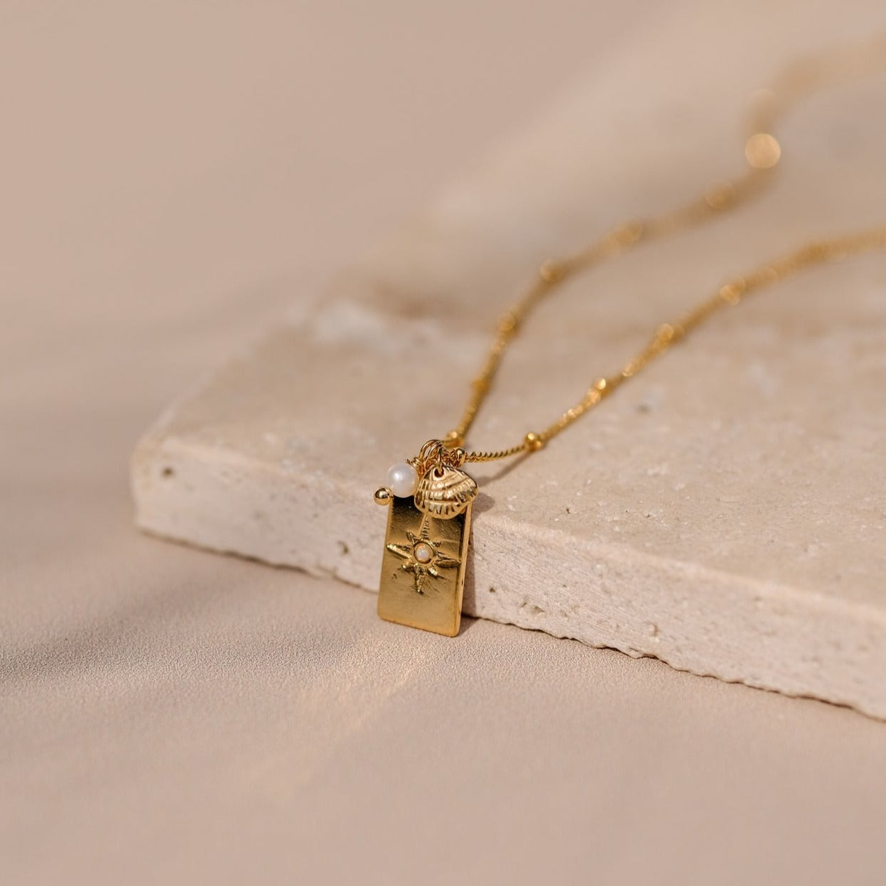 Collier "Dream" composé d'une médaille "étoile du nord" en opale accompagné d'une perle de culture blanche et d'une breloque coquillage monté sur une chaine fine à bille le tout doré à l'or fin.