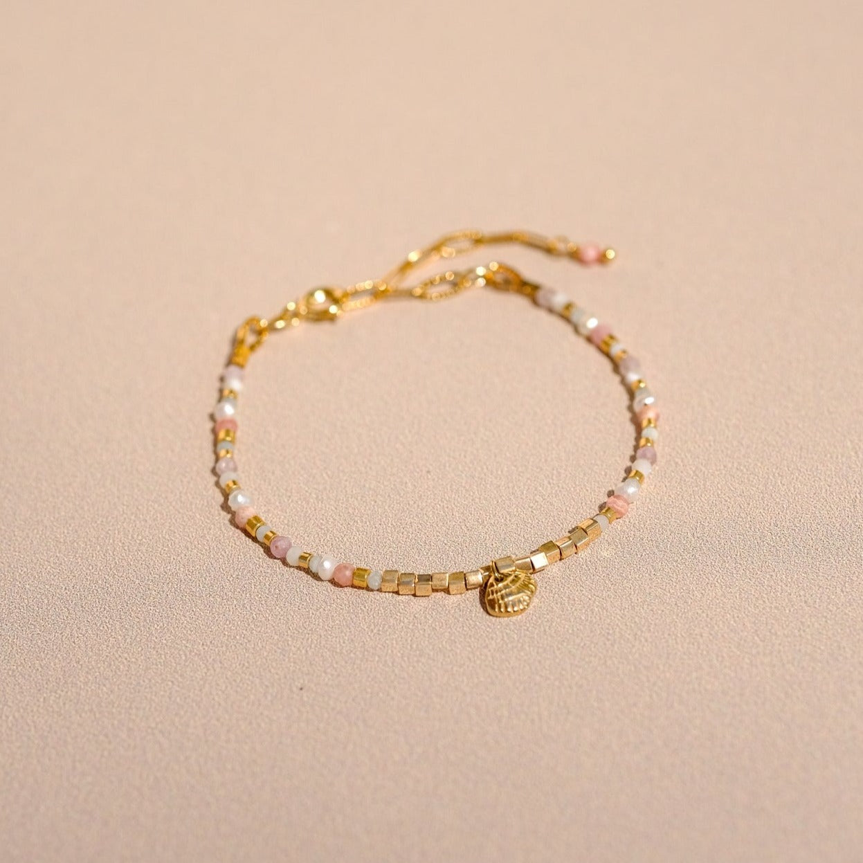 Bracelet "Hope" composé de pierres semi précieuses (perle d'eau, rhodochrosite, kunzite, nacre, amazonite verte et bleue), d'une breloque coquillage ainsi que de perles doré à l'or fin.