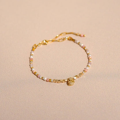 Bracelet "Hope" composé de pierres semi précieuses (perle d'eau, rhodochrosite, kunzite, nacre, amazonite verte et bleue), d'une breloque coquillage ainsi que de perles doré à l'or fin.